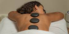Hot black stones aligned on woman's bare back while she lays on hands at The Spa