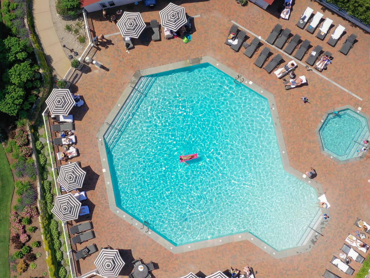 Top down view of blue octagonal pool, brick pool deck, and striped umbrellas, Inn at Bay Harbor