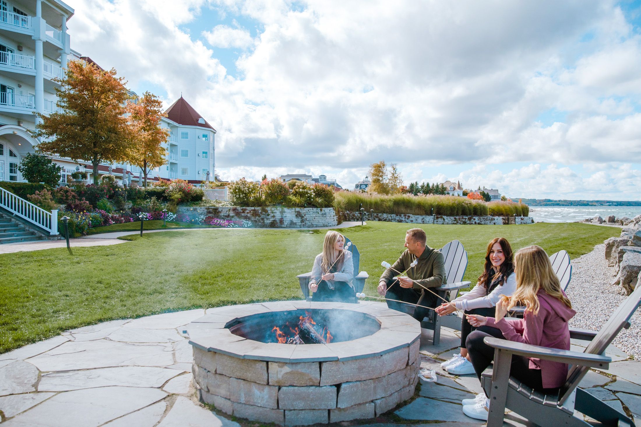 Family laughing and roasting s'mores at Inn at Bay Harbor on an autumn day