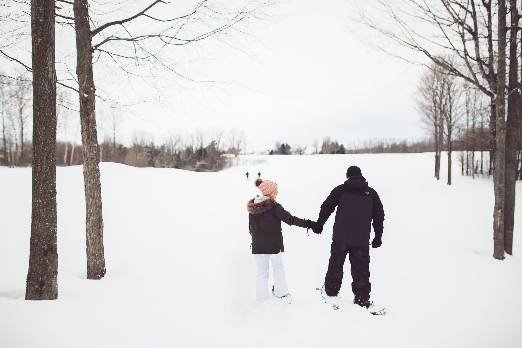 Couple holds hands while snowshoeing, Crooked Tree Golf Club