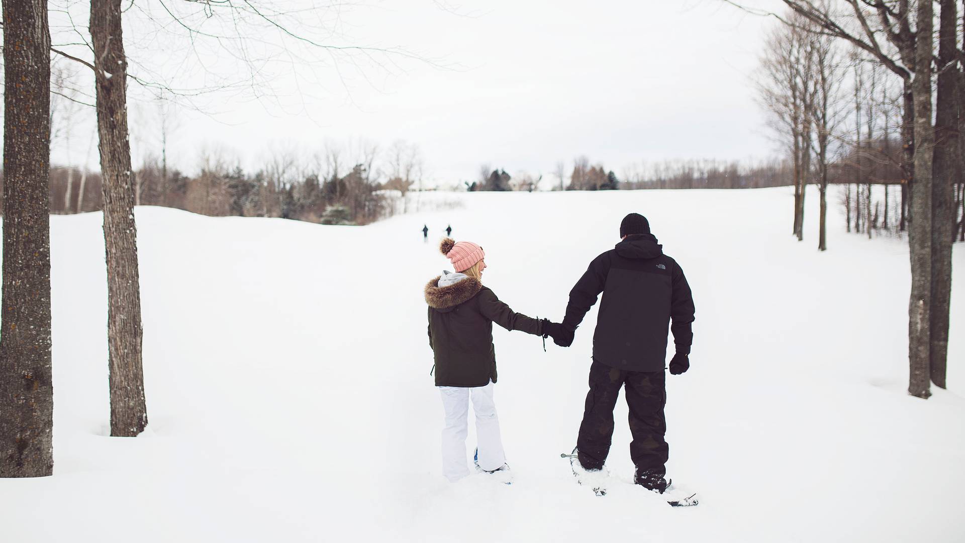 Couple holds hands while snowshoeing, Crooked Tree Golf Club