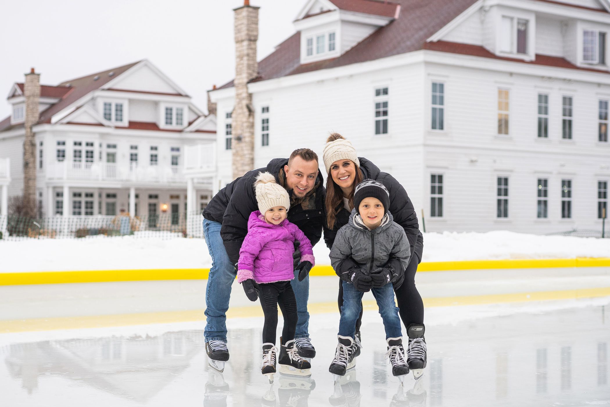 Family smiles at outdoor ice rink, Cottages at Bay Harbor