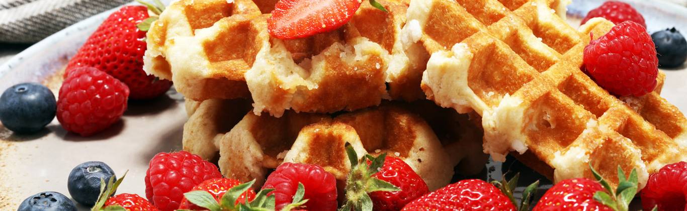 Strawberries, raspberries, and blueberries atop home made waffles.