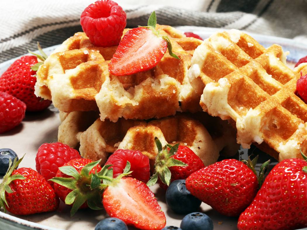 Strawberries, raspberries, and blueberries atop home made waffles.