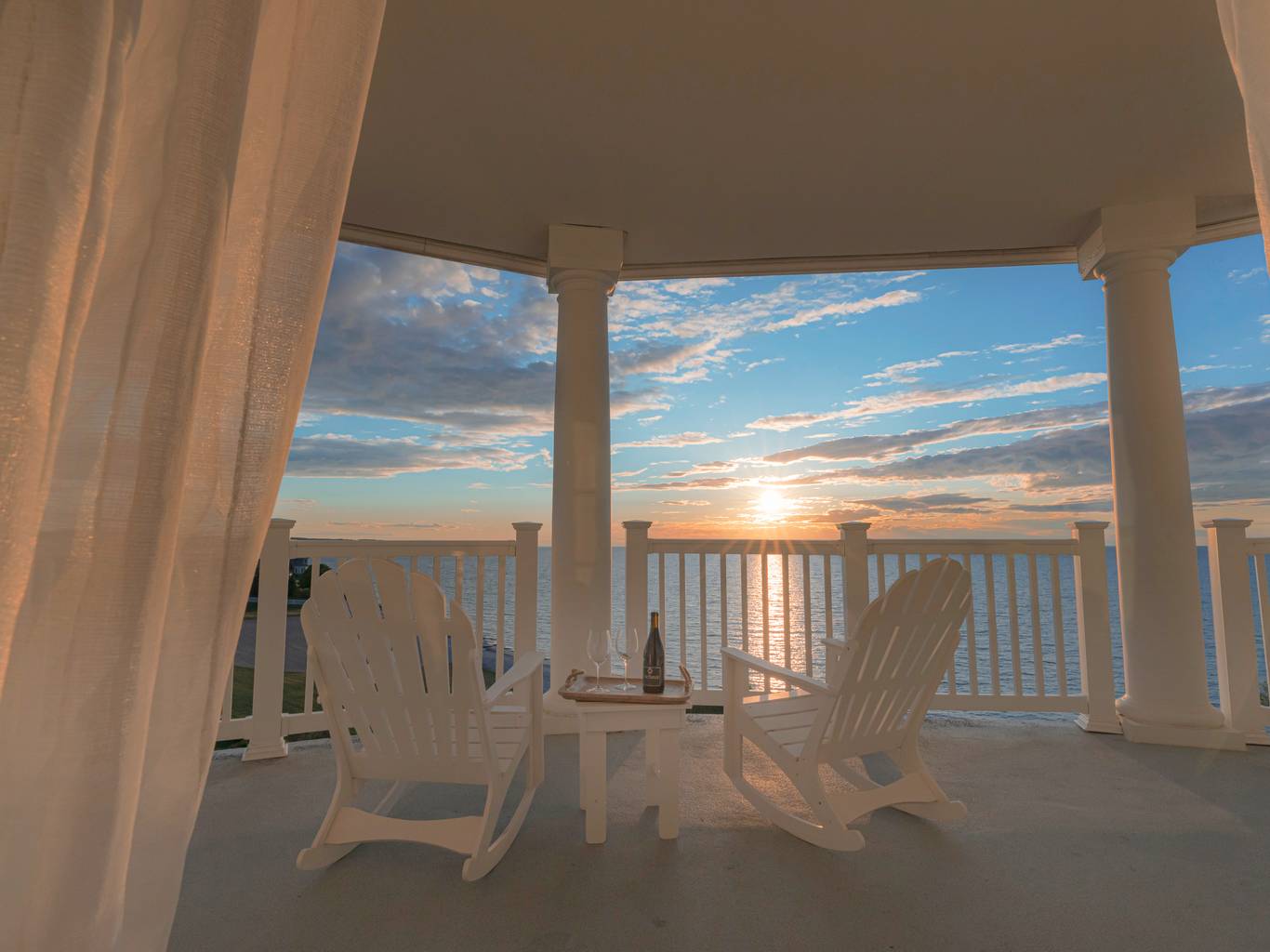 White Adirondack rocking chairs on balcony overlooking sunset on Lake Michigan