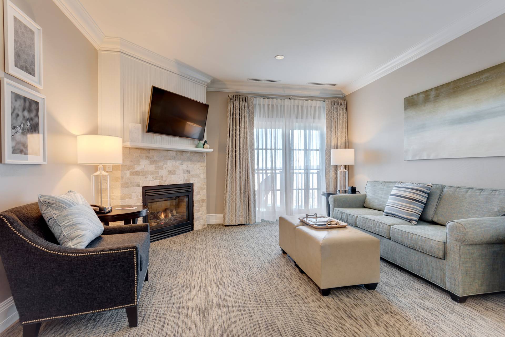 Parlor hotel room living area with neutral couch, dark chair near fireplace, Inn at Bay Harbor