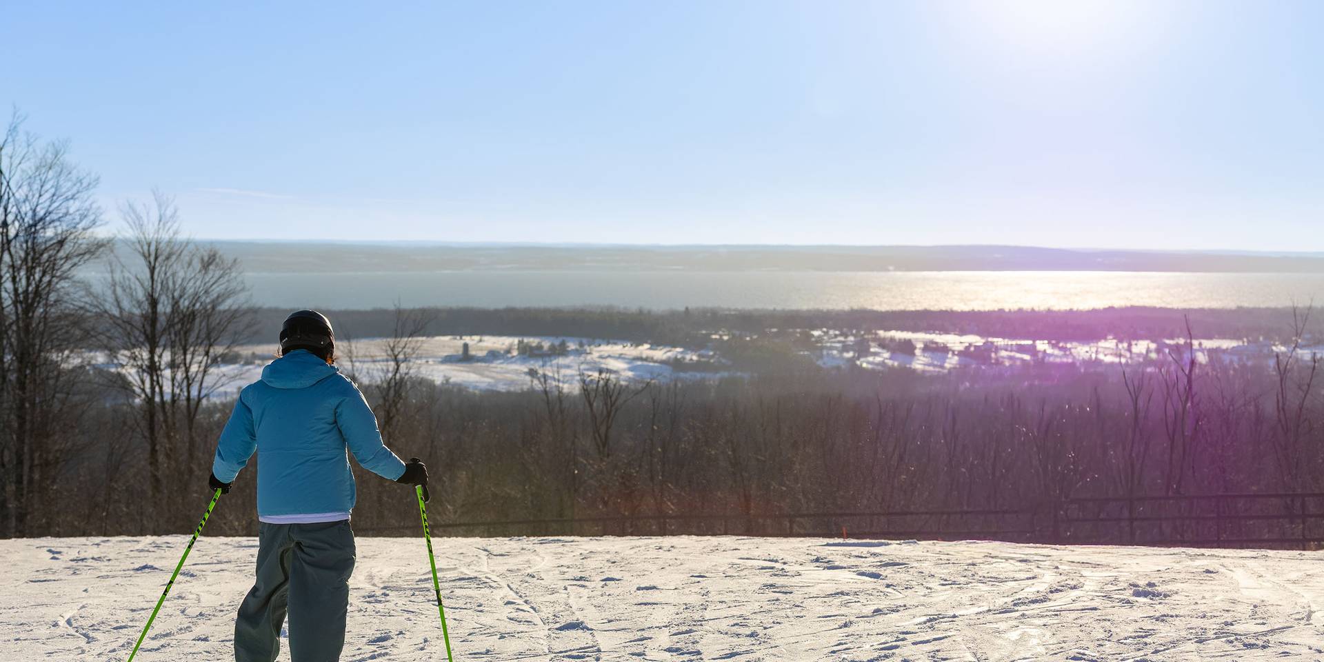 A skier looking at Lake Michigan at the top of Camelot at The Highlands