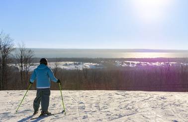 A skier looking at Lake Michigan at the top of Camelot at The Highlands