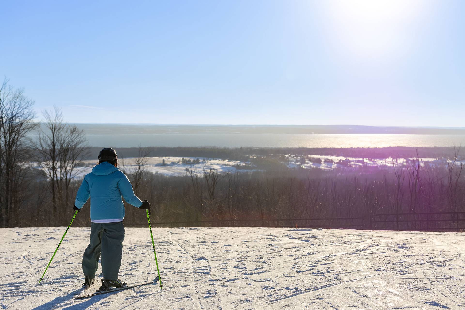A skier looking at Lake Michigan at the top of Camelot at The Highlands