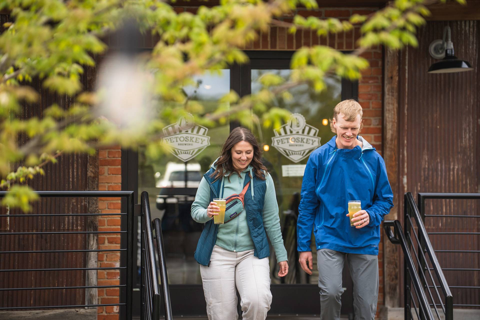 Two people walking with beer in hand at Petoskey Brewing