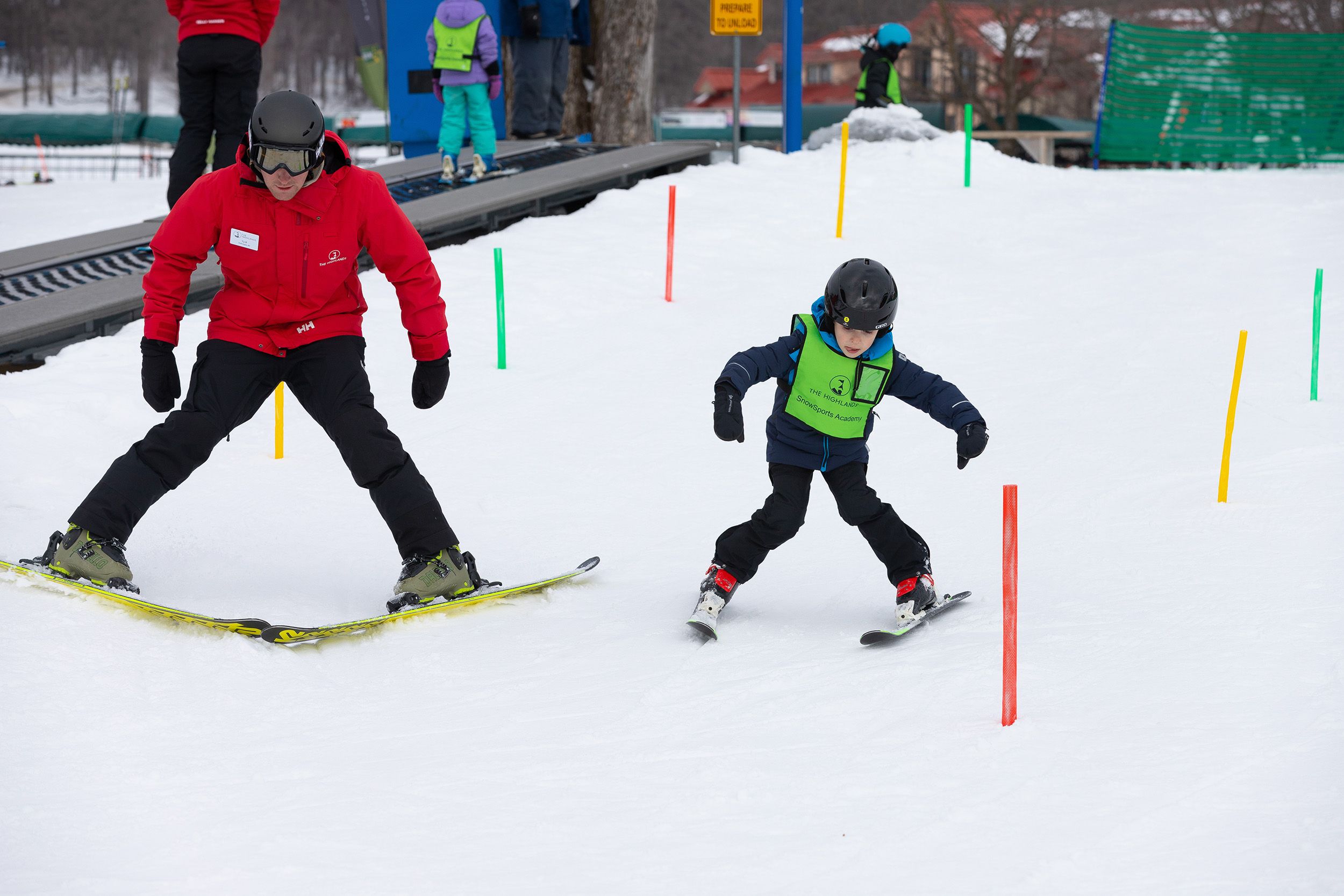 A snowsports instructor and a kid taking a ski lesson at The Highlands