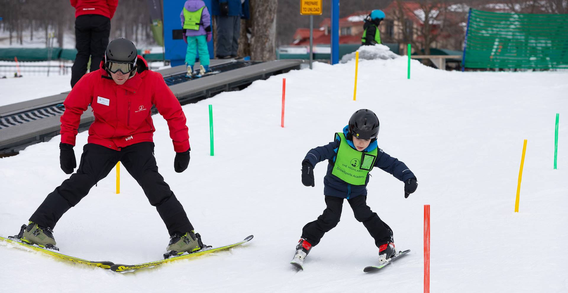 A snowsports instructor and a kid taking a ski lesson at The Highlands