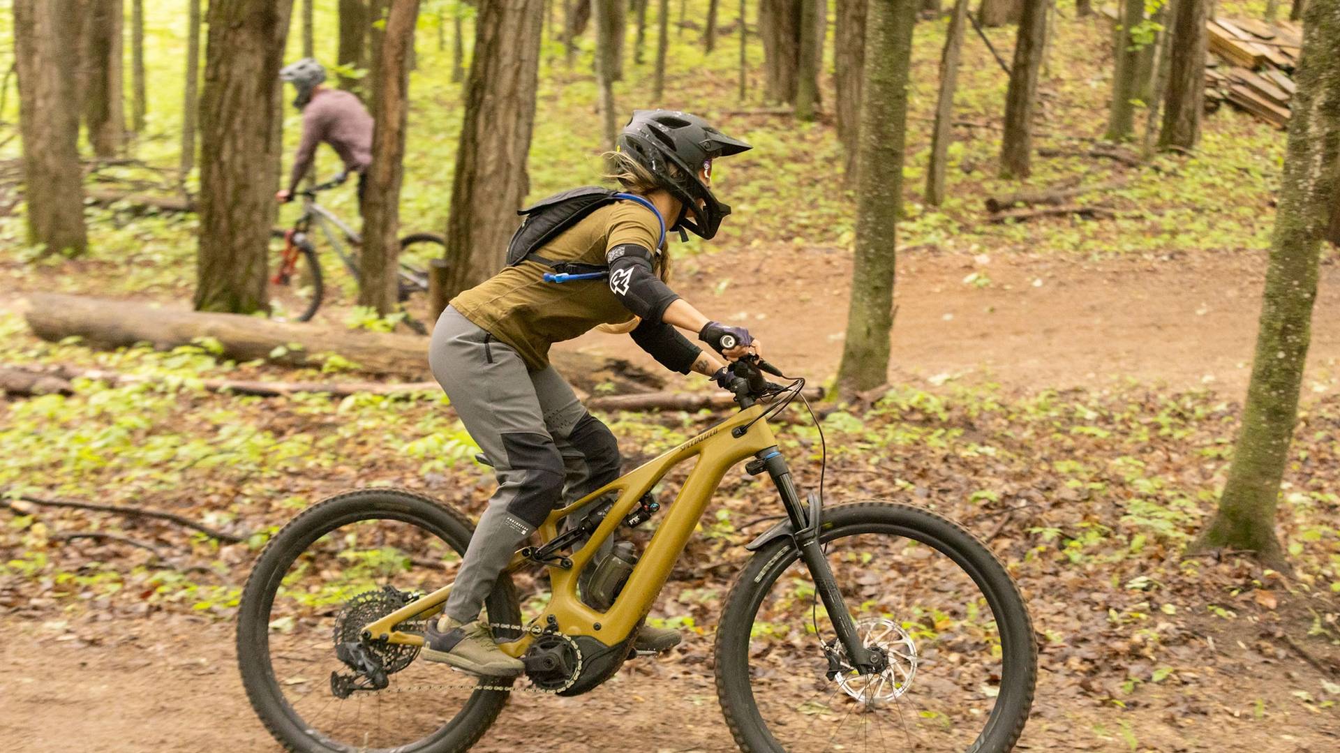 A woman mountain biking on a downhill trail on a yellow bike