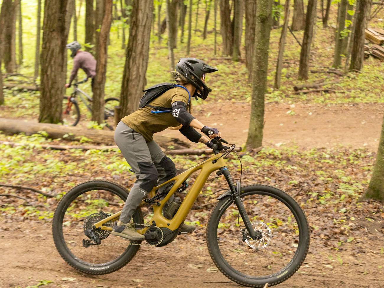 A woman mountain biking on a downhill trail on a yellow bike