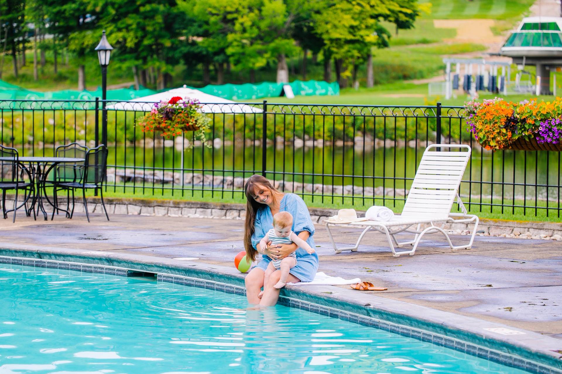 A woman and a baby dipping their toes in an outdoor pool