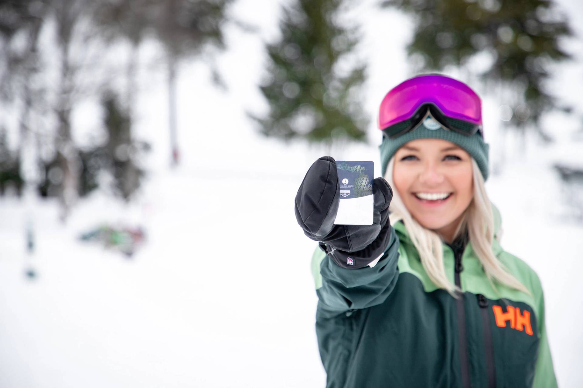 A woman in ski gear holding a Highlands Go Card