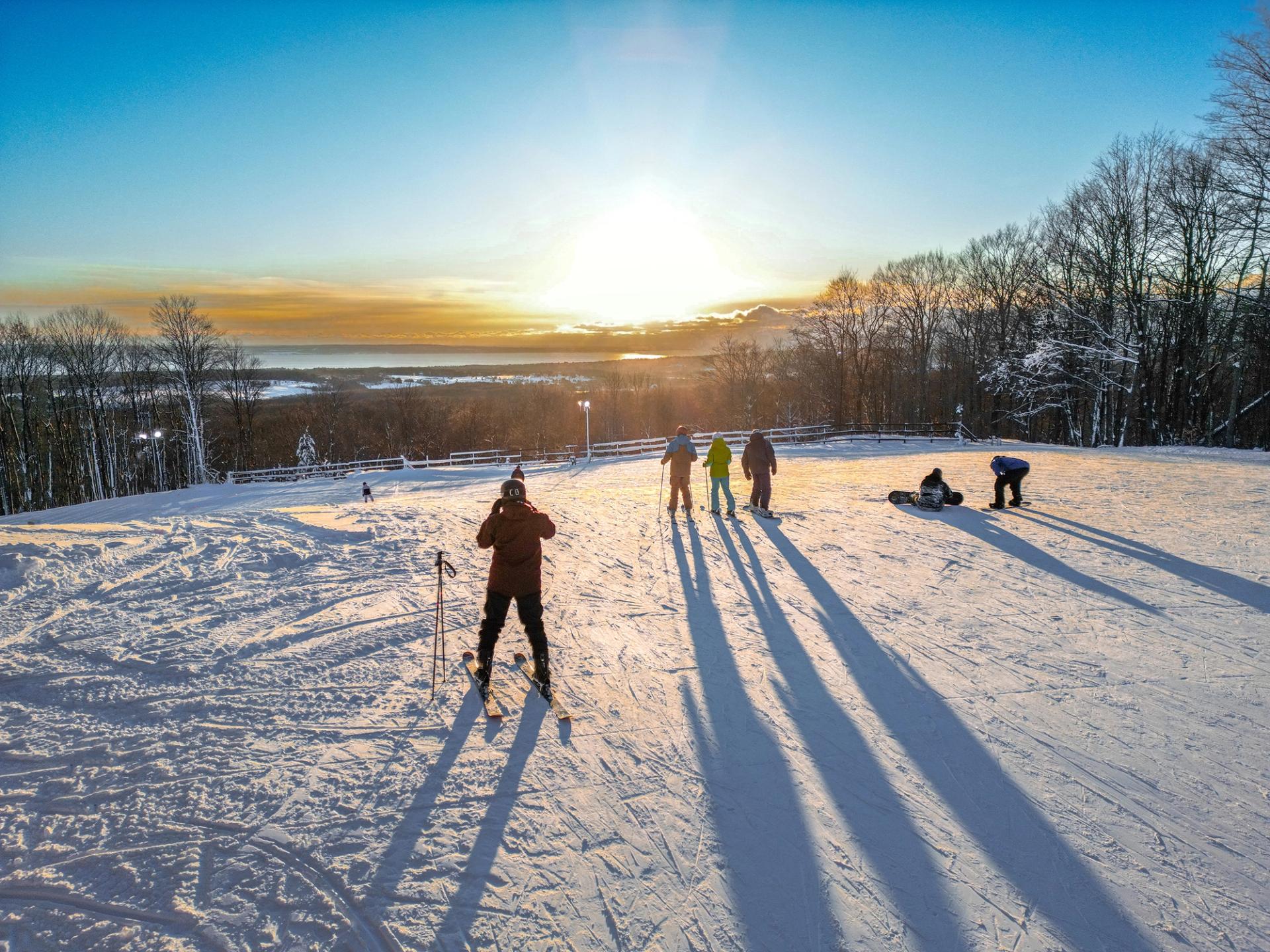 A group of skiers admiring the sunset at the top of the slopes at The Highlands