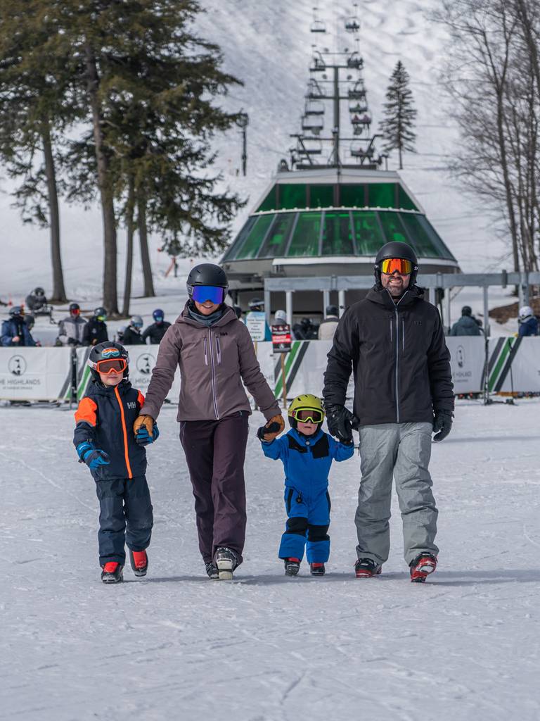 A family in ski gear walking in front of a ski lift
