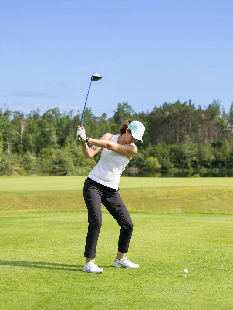 A woman golfing at The Highlands