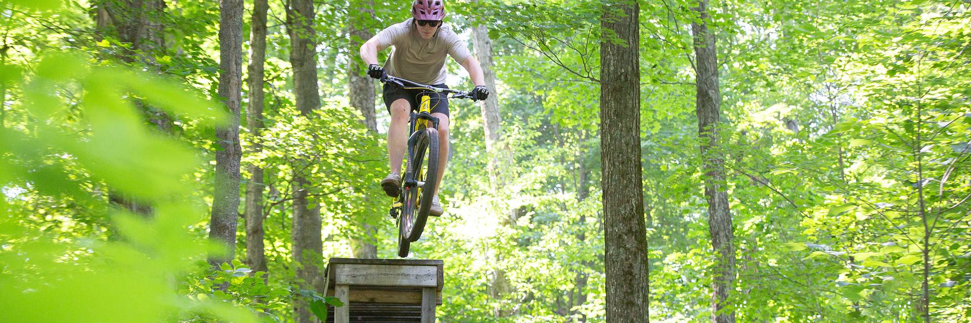 A biker going over a wooden jump feature at The Highlands Bike Park