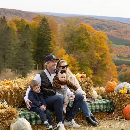 A family posing on a hay bale at The Highlands Harvest Fest