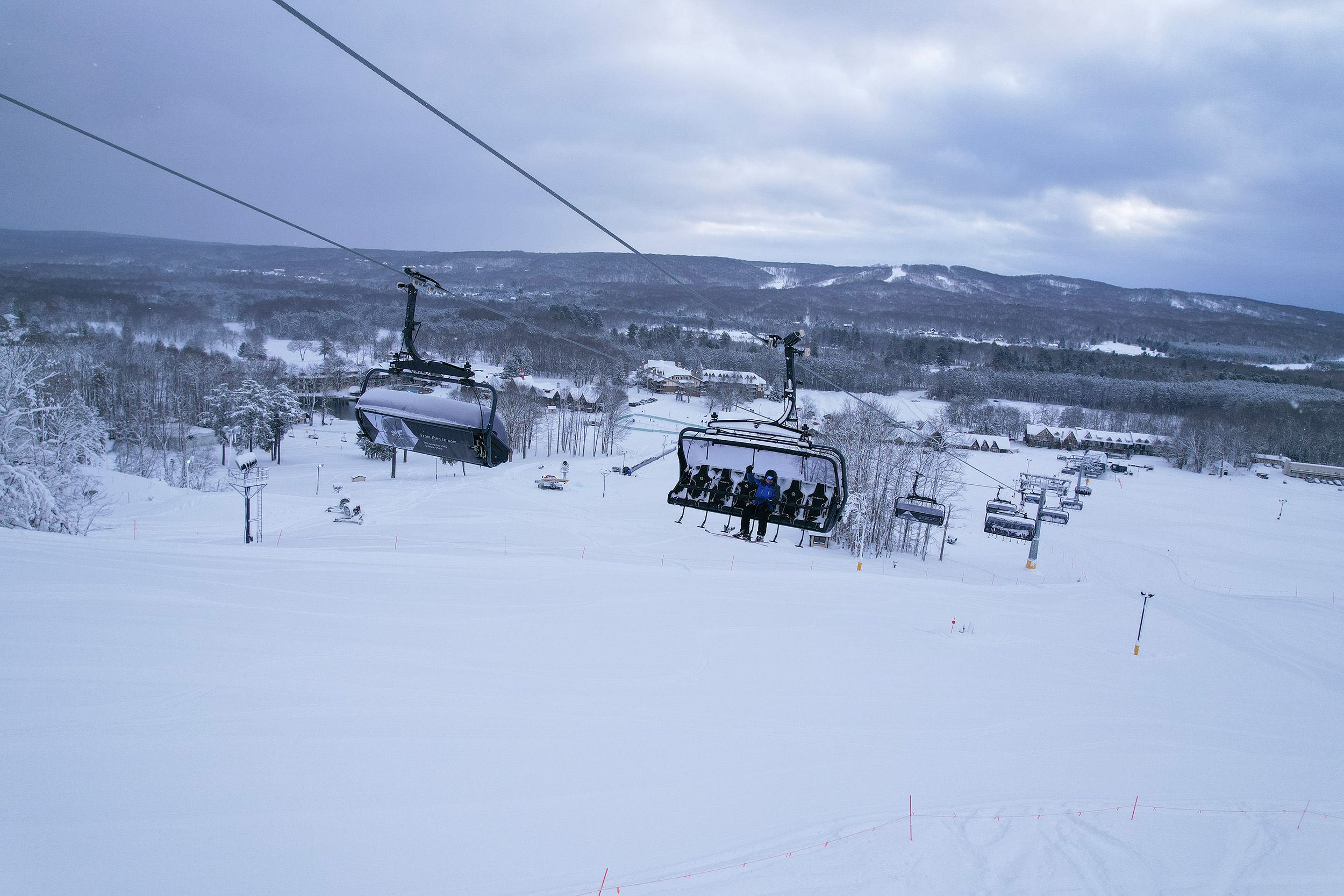 A drone shot of an employee sitting on Camelot 6 chairlift
