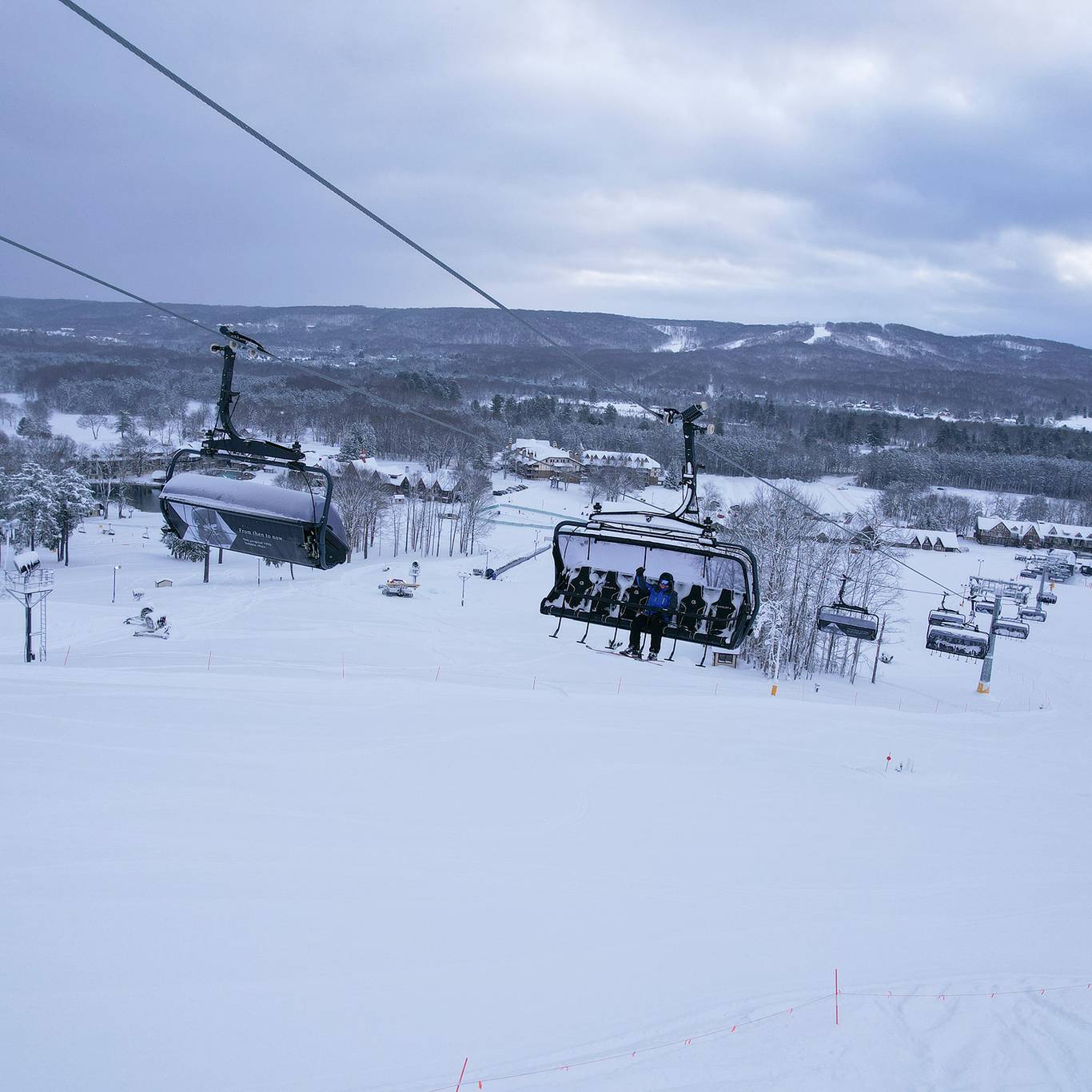 A drone shot of an employee sitting on Camelot 6 chairlift