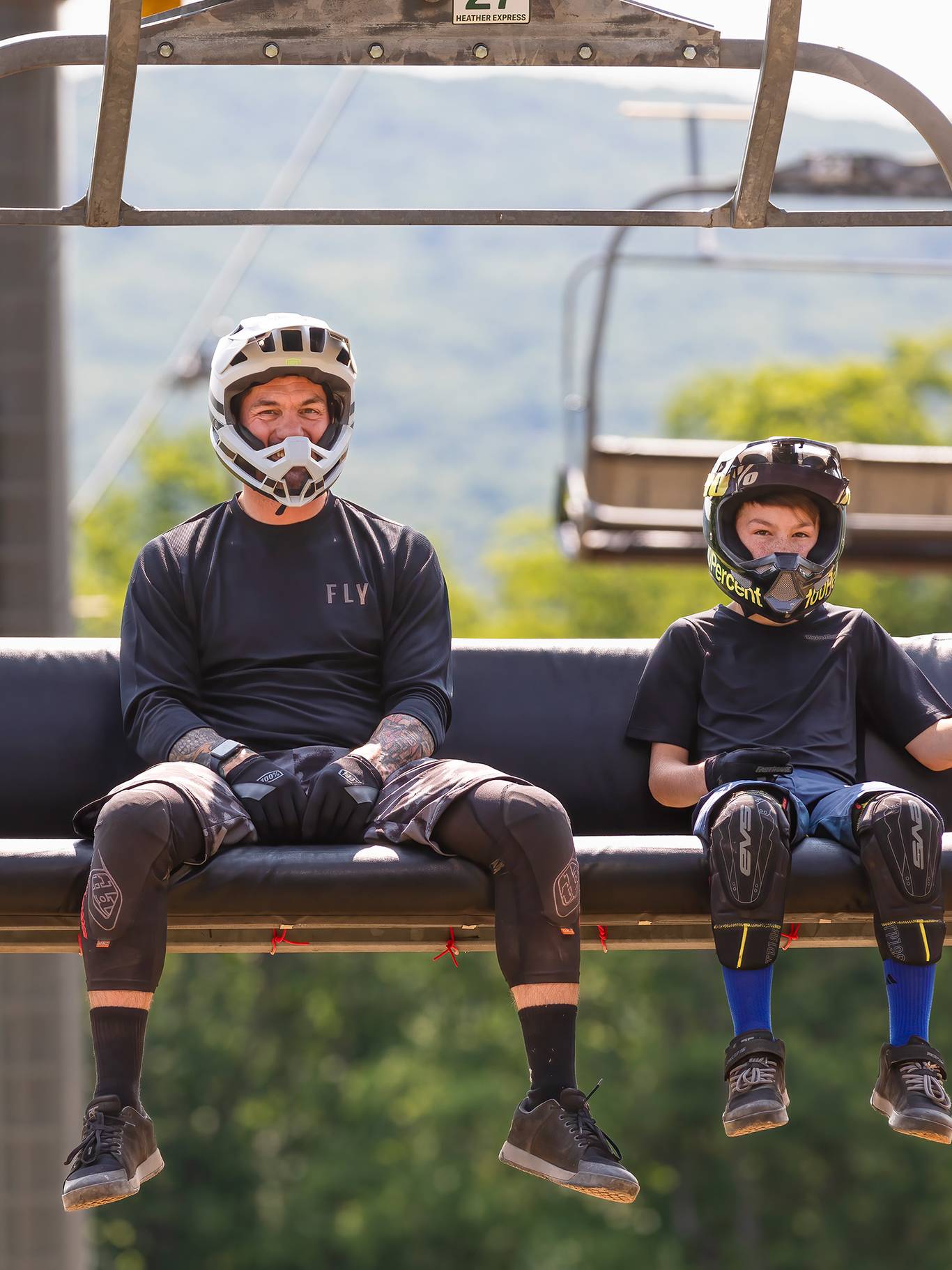 A dad and child in mountain bike gear riding the scenic chairlift