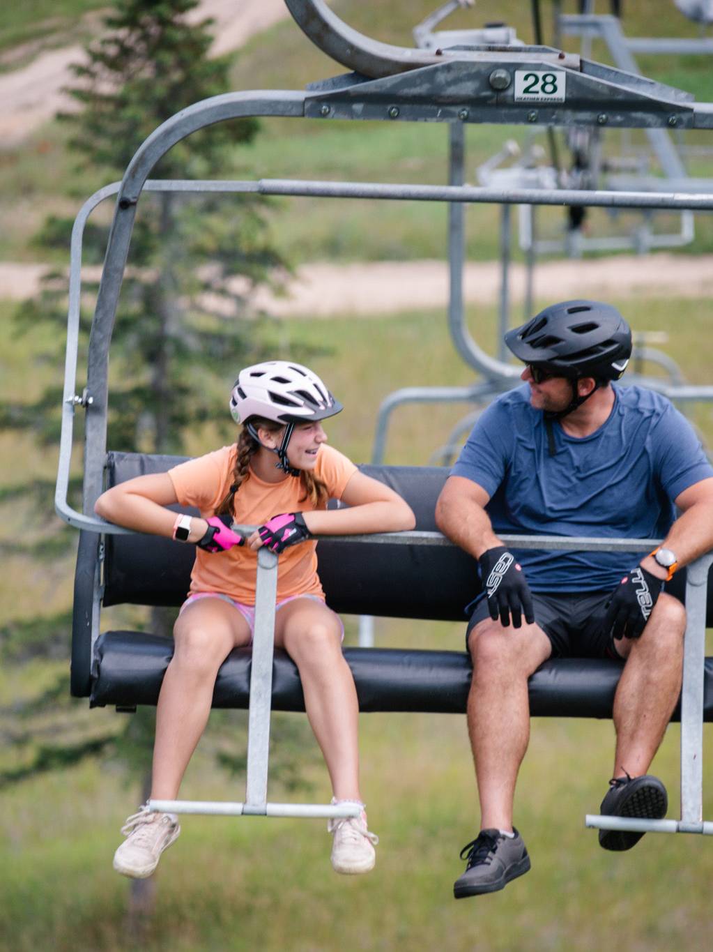 Two bikers sitting on a chairlift at The Highlands