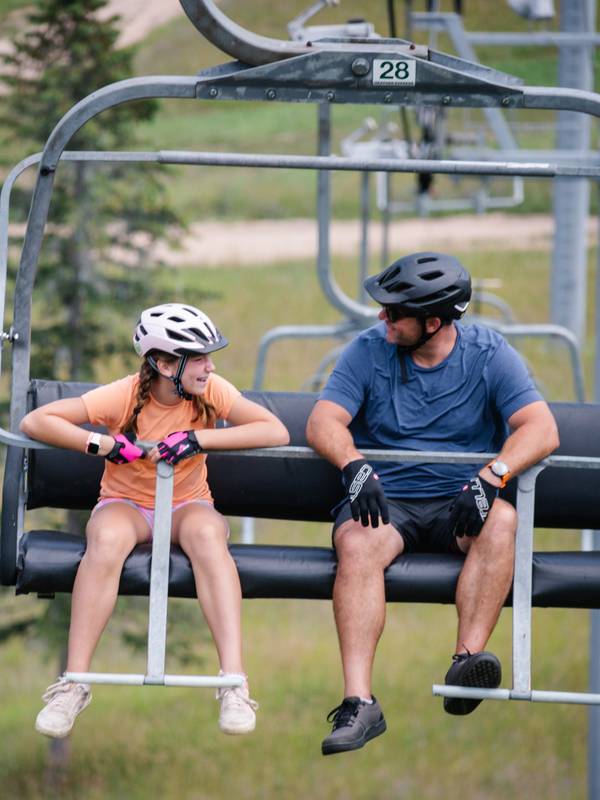 Two bikers sitting on a chairlift at The Highlands