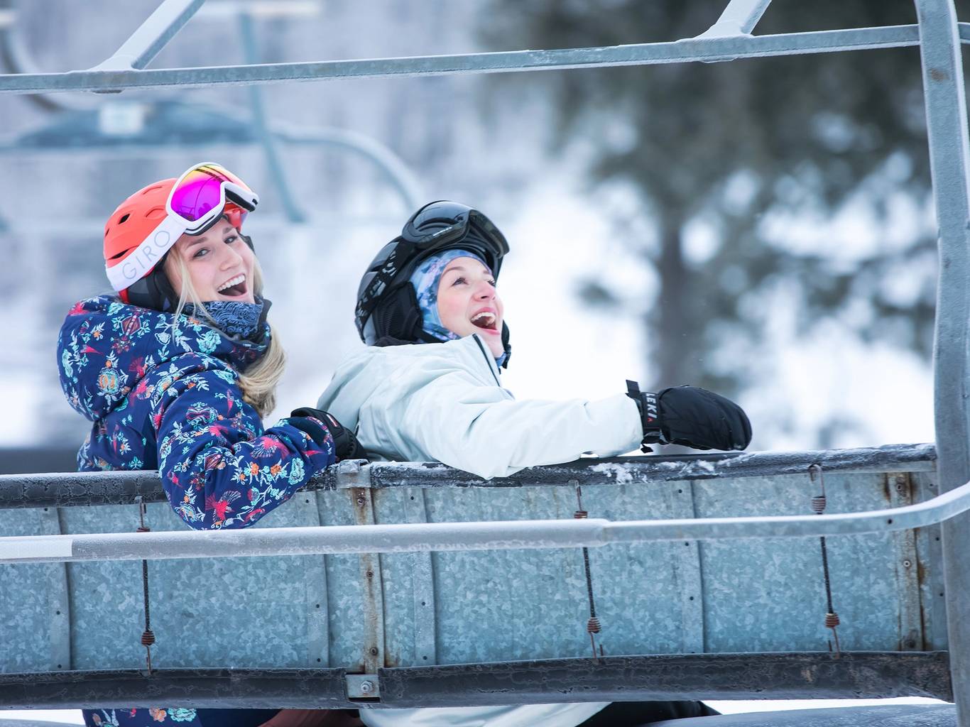 Two women posing in ski gear in a chairlift at The Highlands