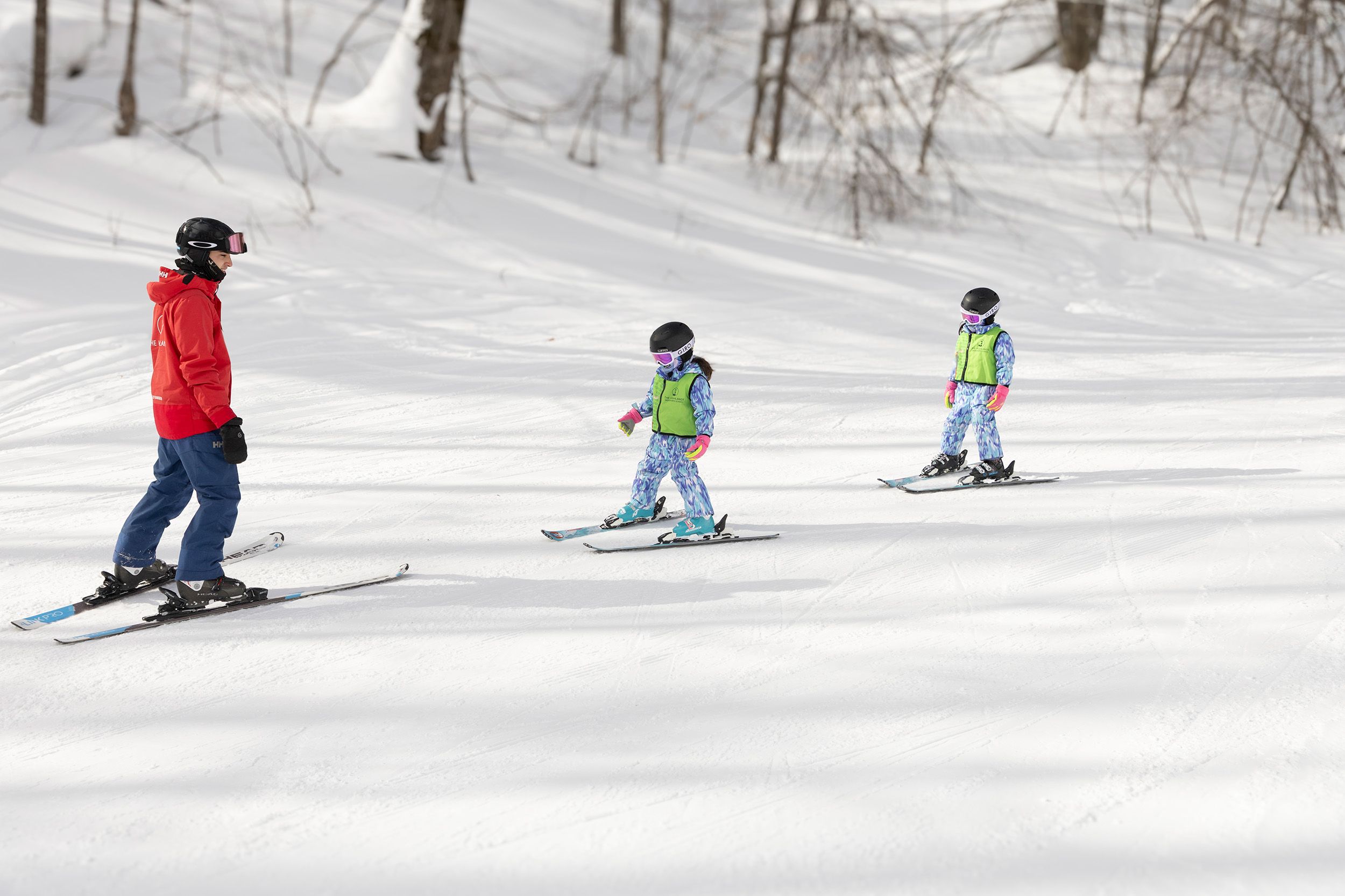 A snowsports instructor and two kids taking a ski lesson at The Highlands