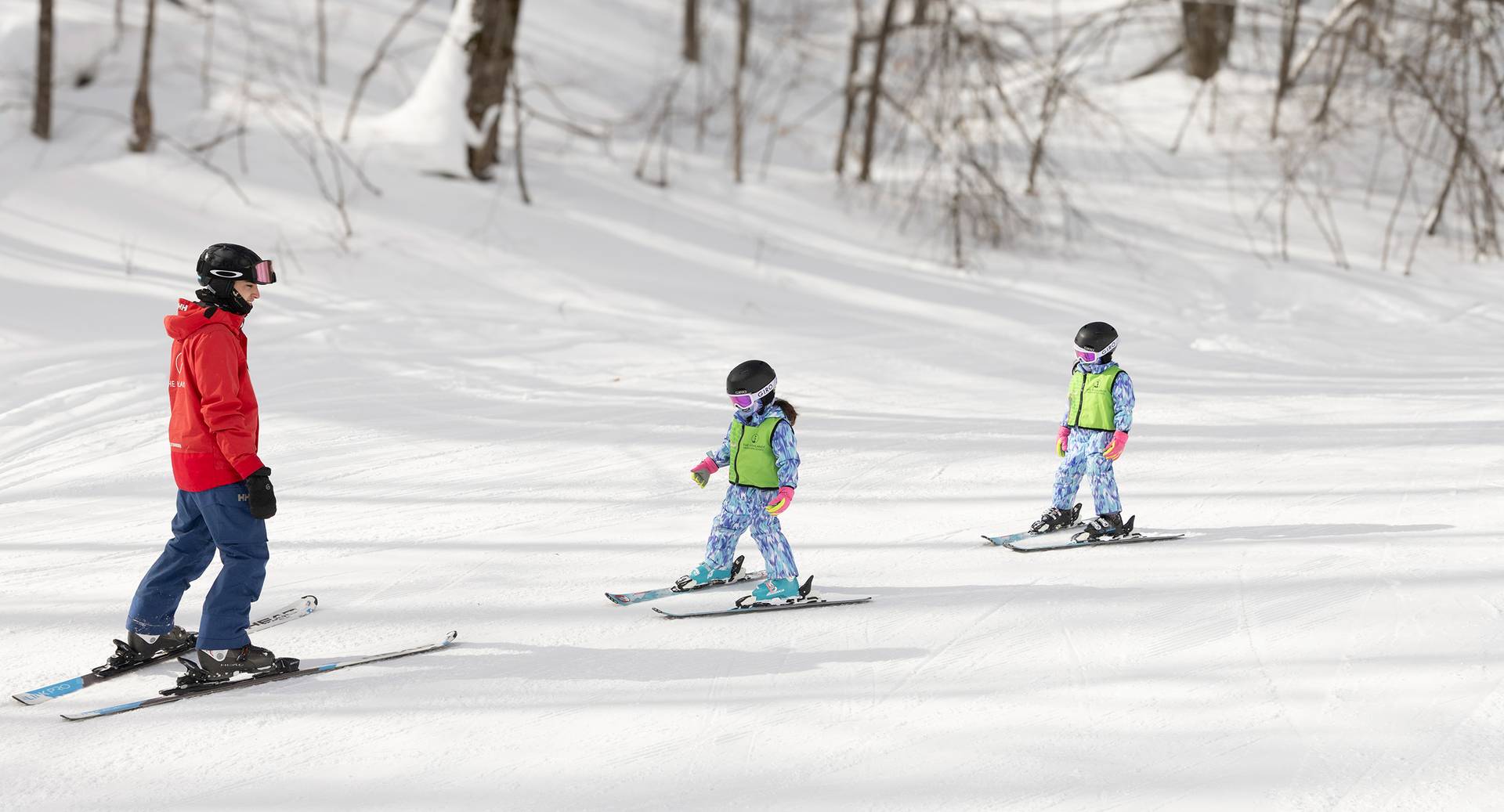 A snowsports instructor and two kids taking a ski lesson at The Highlands