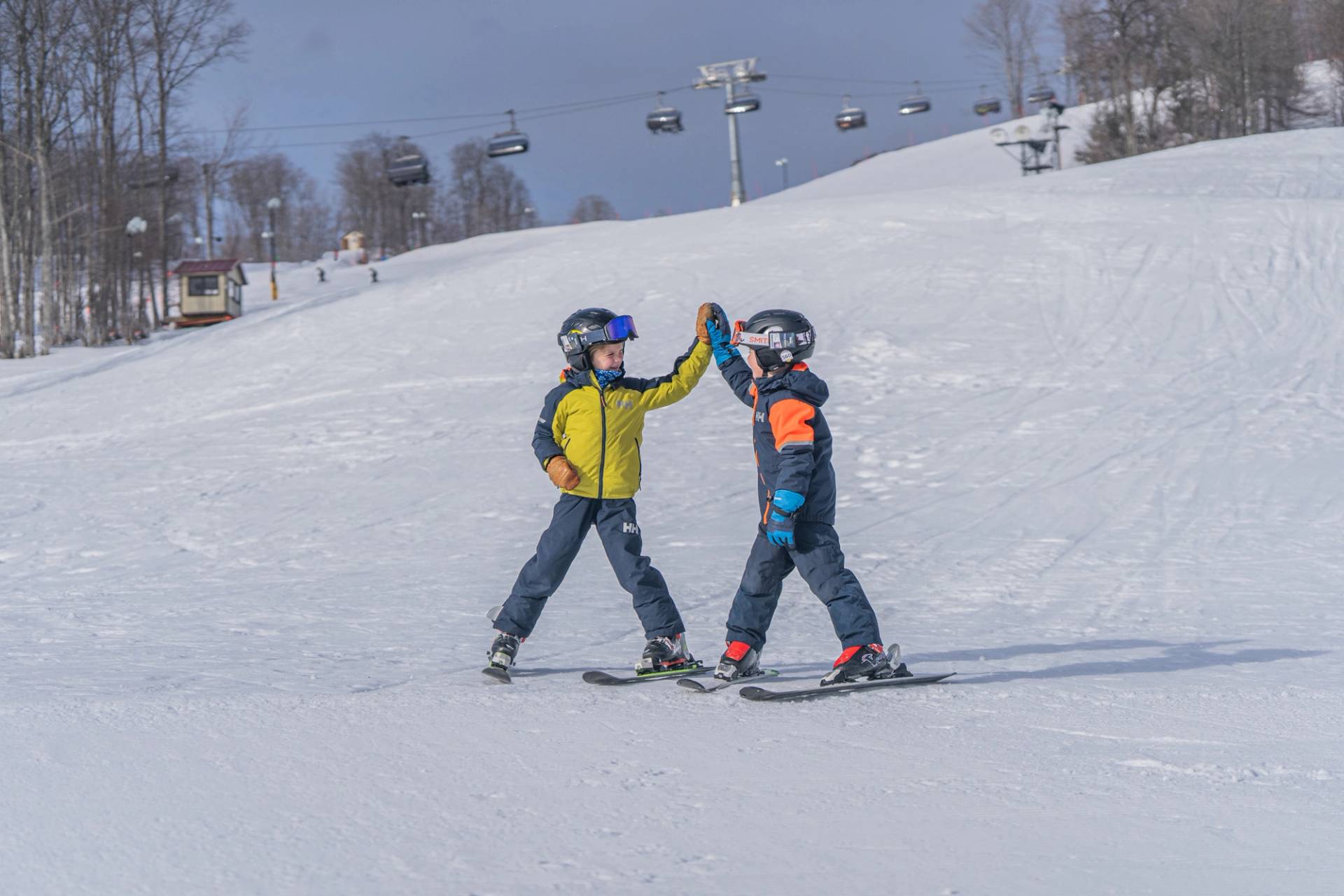 Two kids high-fiving in ski gear at The Highlands