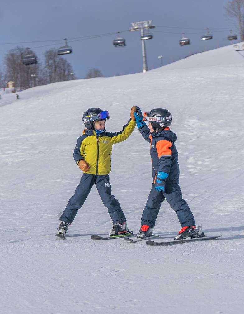 Two boys high fiving in ski gear at The Highlands