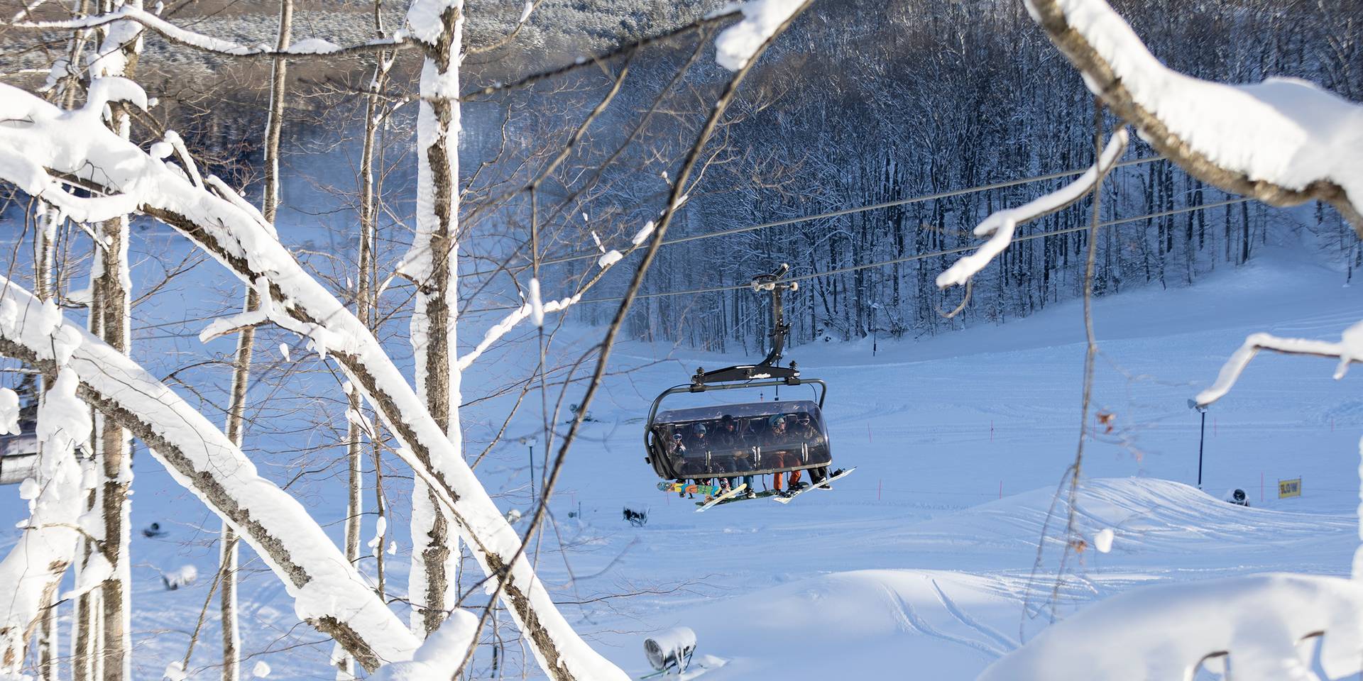 A family in ski gear on Camelot 6 chairlift at The Highlands