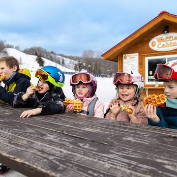 A group of kids eating waffles at the Waffle Cabin