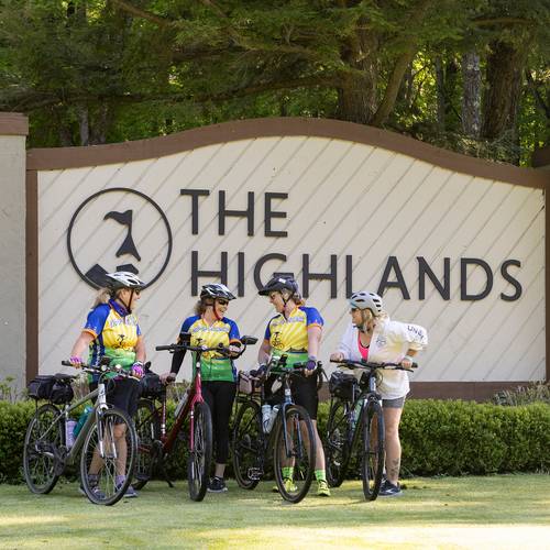 Women bikers posing in front of The Highlands sign