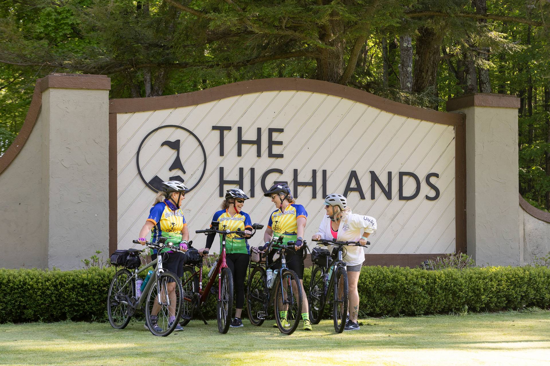 Women bikers posing in front of The Highlands sign