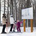 A family in ski gear pointing at a trail map at The Highlands