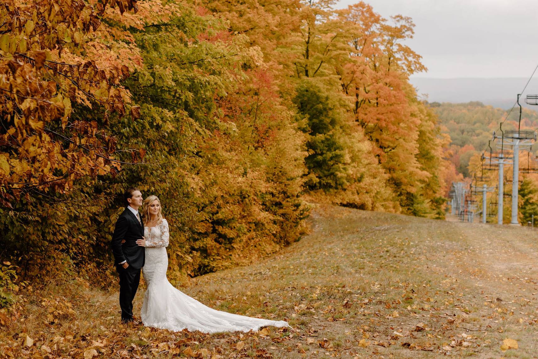 A couple posing near a chairlift in fall