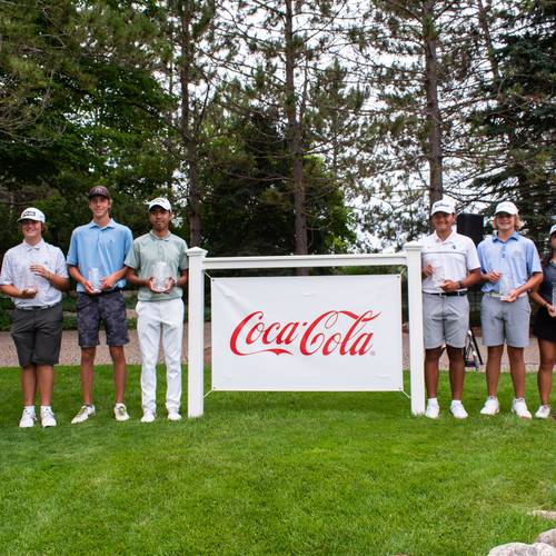 Golfers posing near Coca-Cola sign during AJGA at The Highlands