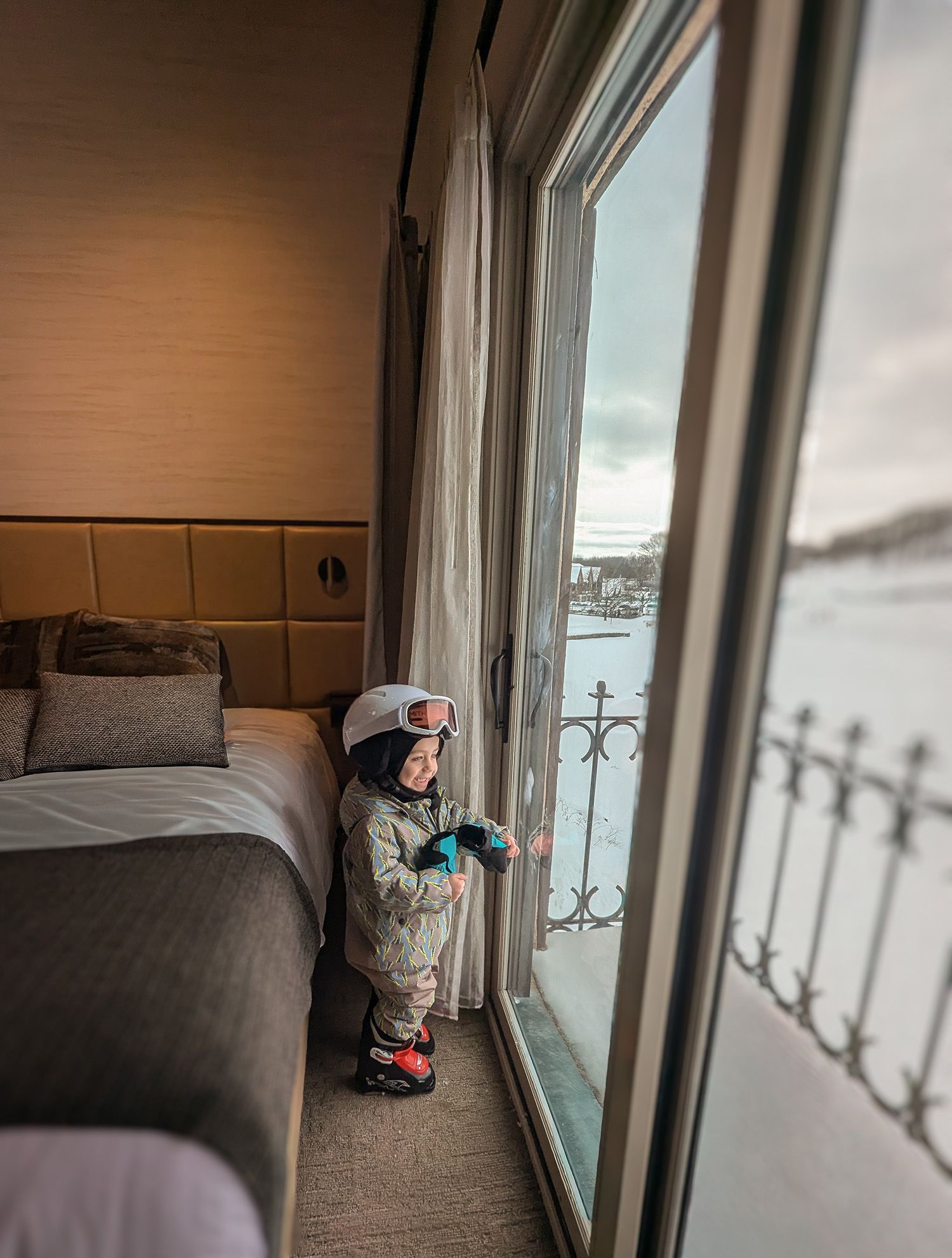 A kid in ski gear staring out the window in the Main Lodge