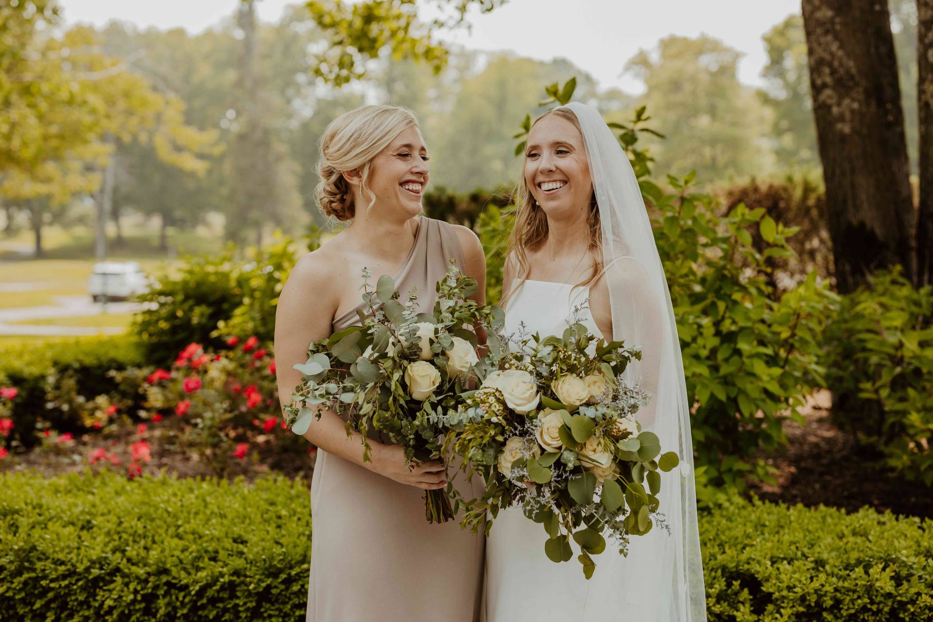 A bride and bridesmaid posing and smiling