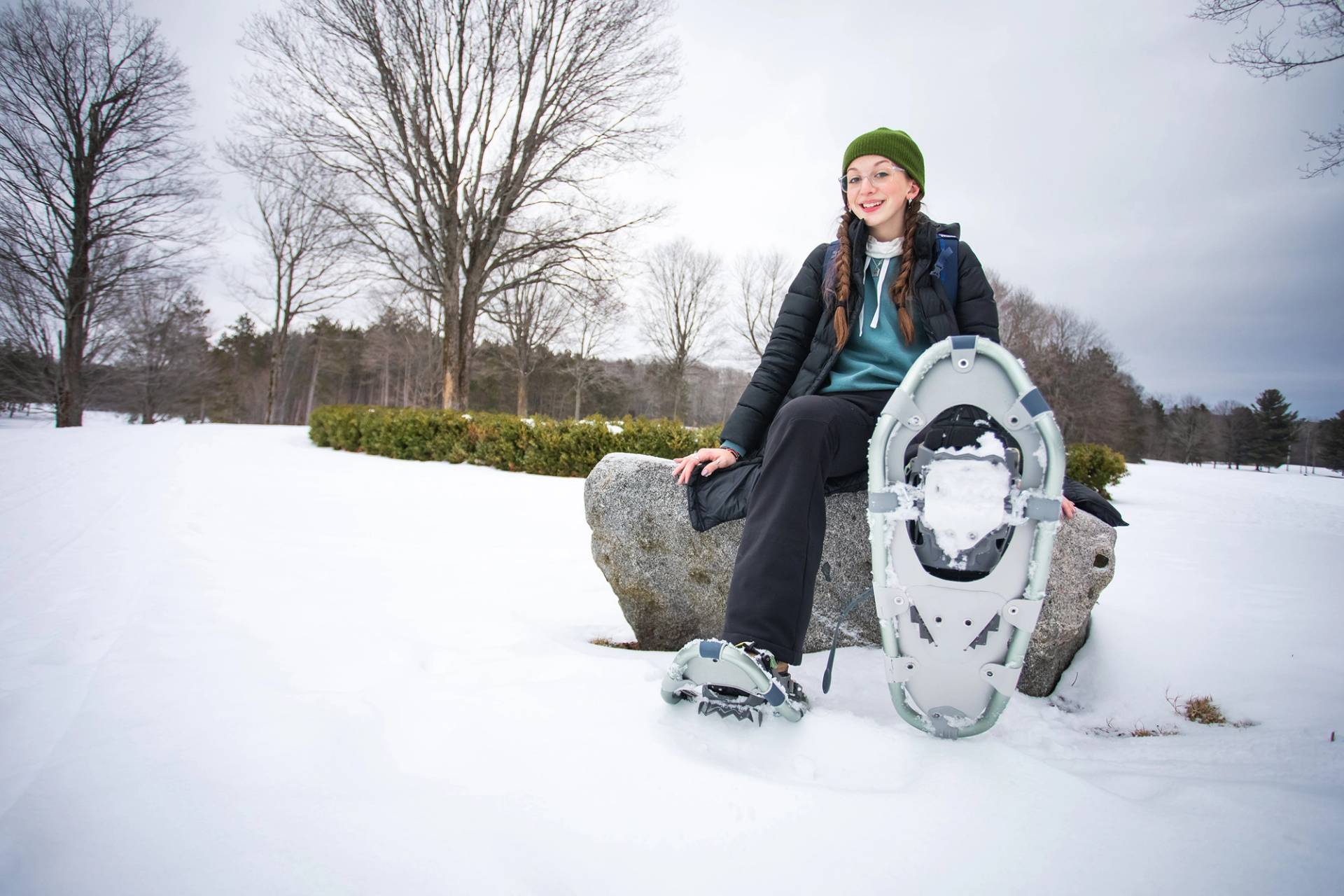 A woman wearing snowshoes posing at The Highlands