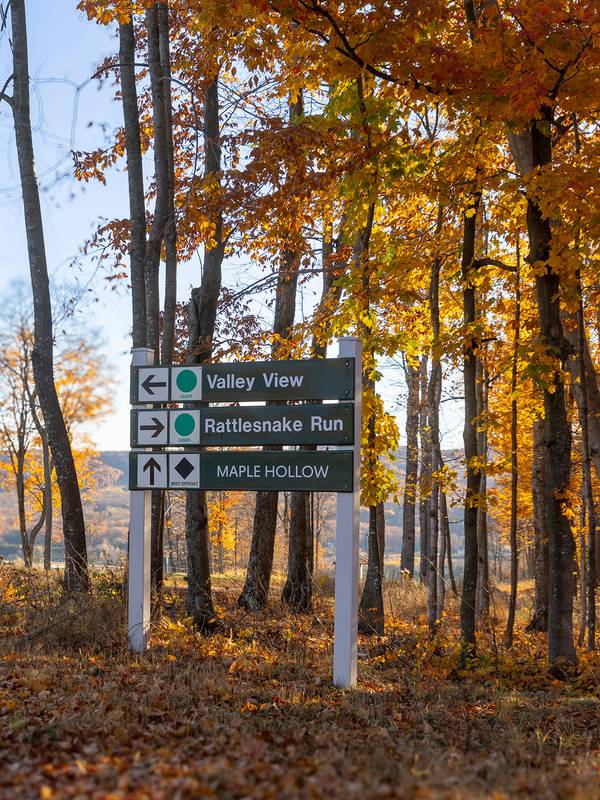 Ski trail sign with a fall backdrop