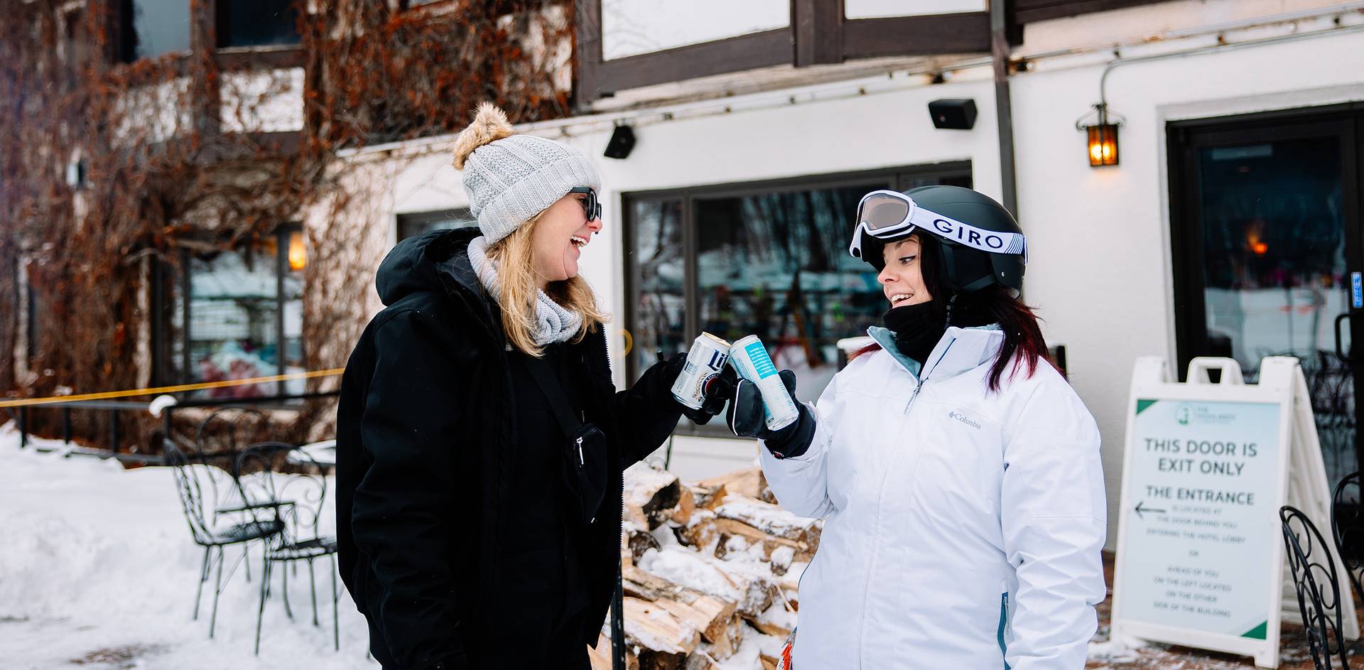 Two woman holding drinks in ski gear at The Highlands
