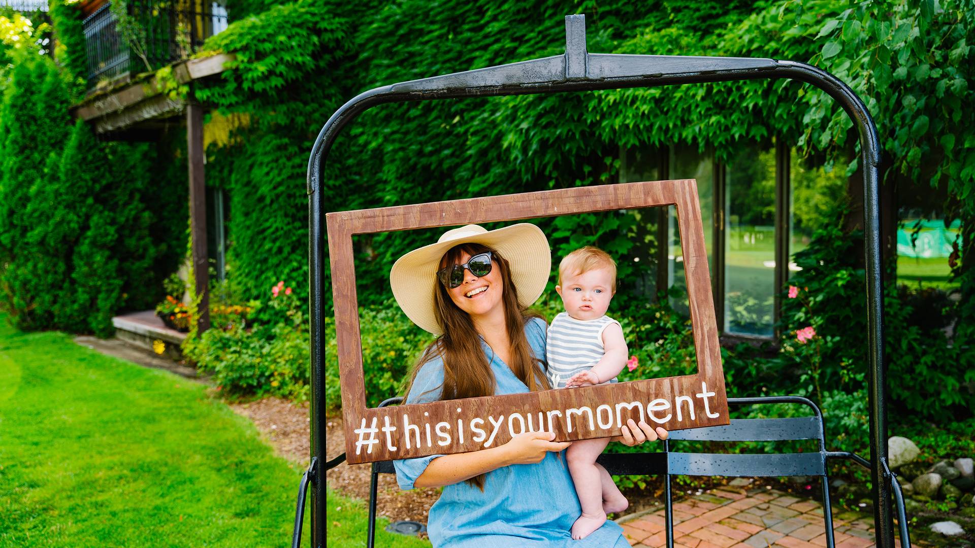 A woman and a baby posing with a wooden sign
