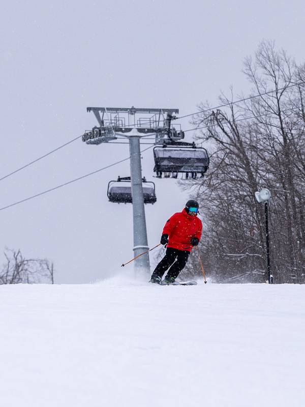 A skier in a red coat skiing by Camelot 6