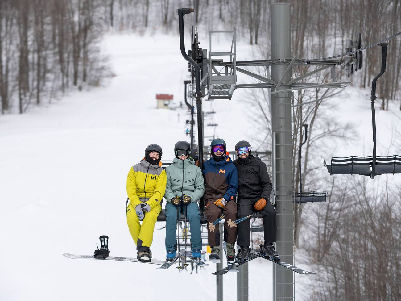A group of skiers and snowboarders posing on the chairlift